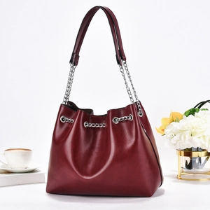 Chic burgundy bucket bag with silver chain drawstring and shoulder strap in a stylish setup