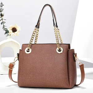 Close-up of brown chain handbag with textured fabric and elegant gold metal hardware