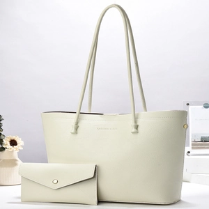 Set borsa tote e pochette bianco sporco con trama a venature in un ambiente minimalista