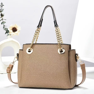Detail of khaki twill woven tote bag featuring black leather handles and gold chain accents