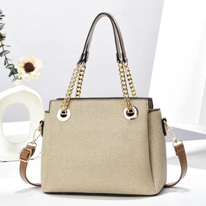 Fashionable beige woven handbag with brown leather straps and gold chain details