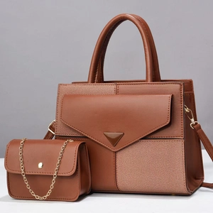 Macro detail of caramel brown patchwork tote bag set with metal buckle and chain strap