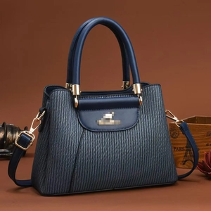 Detail of navy blue crossbody bag with unique vertical wave texture and gold hardware