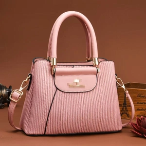 Pink pleated handbag with three layers and gold hardware on warm brown background