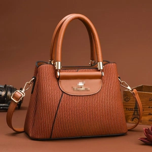 Detail of caramel brown handbag showing vertical wave texture and gold hardware
