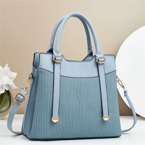Detail of light blue crossbody bag with gold hardware and vertical pleated texture