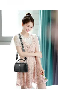 Detail of black litchi texture handbag with a black and white geometric wide strap