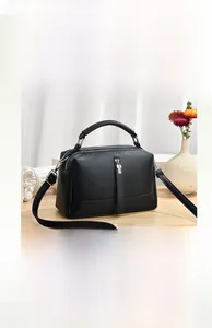 Detail of black pebbled leather mini doctor bag with top handle and fine shoulder strap