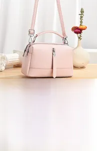 Detail of pink faux leather mini crossbody bag with top handle and vertical zipper accent
