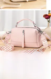 Detail of pink lychee leather bag featuring a wide geometric strap and silver zippers