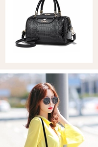 Detail of black crocodile embossed boston bag with golden kangaroo logo and adjustable strap