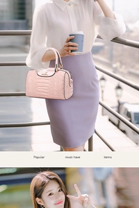 Close-up of pink crocodile texture Boston bag with golden metal hardware and top handles