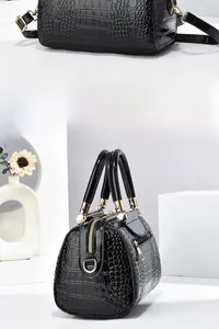 Detail view of black glossy crocodile pattern leather tote with golden hardware zippers