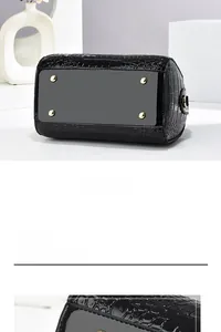Detail view of black crocodile pattern leather bag with protective gold metal feet