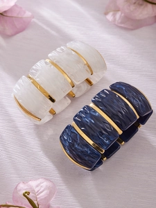 Detail of marble pattern resin bracelets with golden metal beads on a floral background