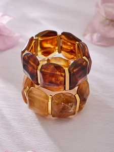 Detailed macro view of geometric resin bangles with amber tones and gold metal spacers
