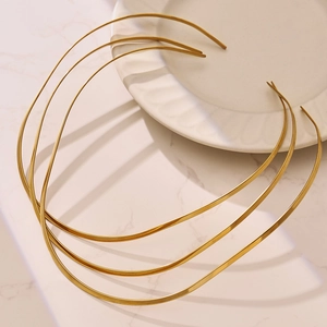 Lot de trois colliers rigides minimalistes plaqués or 18 carats sur fond de marbre blanc