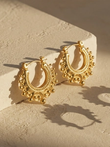 Detailed view of gold C-shaped earrings with textured beads and retro relief pattern