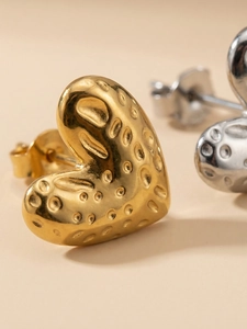 Macro shot of gold heart stud earring with unique hammered texture and metallic finish