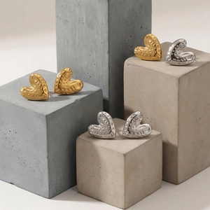 Hammered textured heart stud earrings in gold and silver finish on stone display