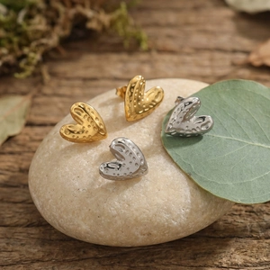 Hammered heart earrings in gold and silver finish on pebble with leaf accent