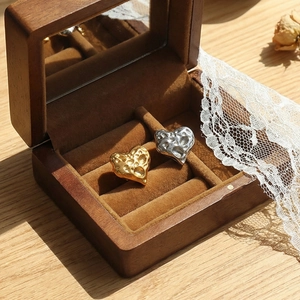Gehämmerte herzförmige Ohrringe in Gold und Silber, präsentiert in einer hölzernen Schmuckschatulle