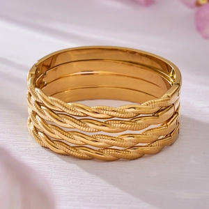 Set of 4 twisted rope bangles in 18k gold plated stainless steel on wooden surface