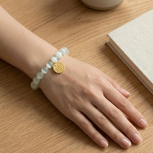 Cat's eye stone bead bracelet with a gold-plated Fu character charm worn by a model