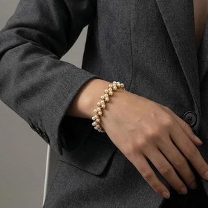 Bracelet multi-rangs en perles et or élégant porté au poignet par un mannequin
