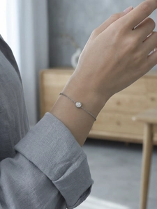 Nahaufnahme eines minimalistischen Silberkettenarmbands mit rundem Kristall am Handgelenk