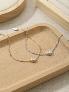 Detail von minimalistischen Gold- und Silberketten mit rundem Zirkonia in Zargenfassung