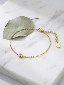 Detail eines 18k vergoldeten Armbands mit Zirkonia und dekorativem Blatt auf Marmor