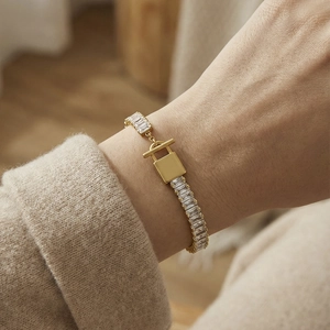 Bracciale a catena in acciaio dorato con zirconi e pendente a forma di lucchetto
