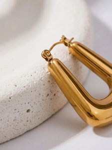 Macro detail of polished U-shaped 18k gold plated stainless steel hoop earrings