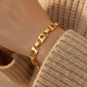 Bracelet floral évidé en acier inoxydable doré sur poignet avec fond de pull en maille beige