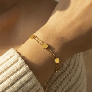 Double-layered 18k gold plated stainless steel bracelet with three heart pendants on a model