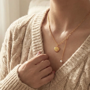 Collier chic avec pendentif cœur doré, perle et chaîne asymétrique sur pull en maille