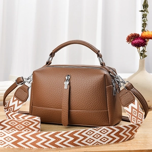 Brown lychee leather crossbody bag with top handle and geometric patterned fabric strap