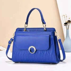 Detail of royal blue quilted handbag featuring a gold pearl buckle and stitching