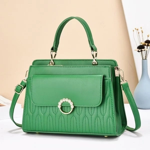 Detailed macro view of the emerald green pleated leather handbag with pearl ring buckle