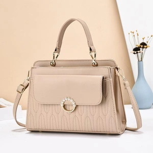 Detail of beige quilted handbag with pearl ring buckle and adjustable shoulder strap