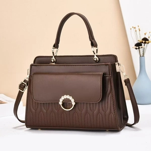 Detail of dark brown quilted handbag featuring a pearl buckle and wave stitch pattern