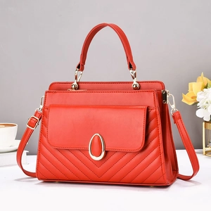 Detail of red leather handbag with V-shaped quilting and gold oval twist lock closure