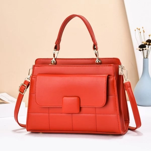 Detail of red quilted PU leather handbag with golden hardware and top handle