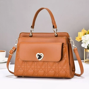 Close-up of caramel leather handbag with heart quilting and elegant metal buckle