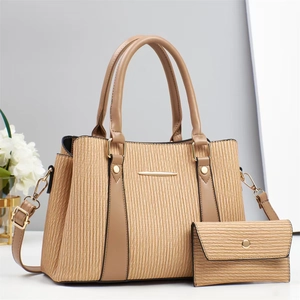 Close-up of khaki pleated tote set with smooth brown handles and gold hardware accents