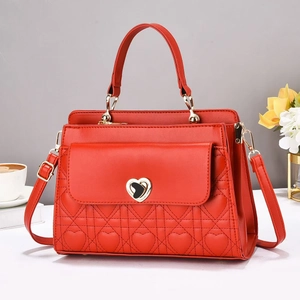 Detailed view of red quilted handbag featuring a gold heart-shaped metal twist lock closure