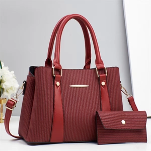 Detail view of burgundy tote bag set with textured vertical patterns and gold hardware