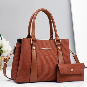 Detail of brown textured handbag set with wave pattern and golden metal accents