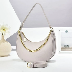 Detail of crescent moon bag with lychee texture leather and gold chain strap accent